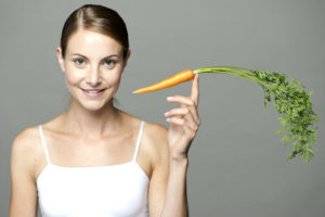 Девушка держит морковь в руке